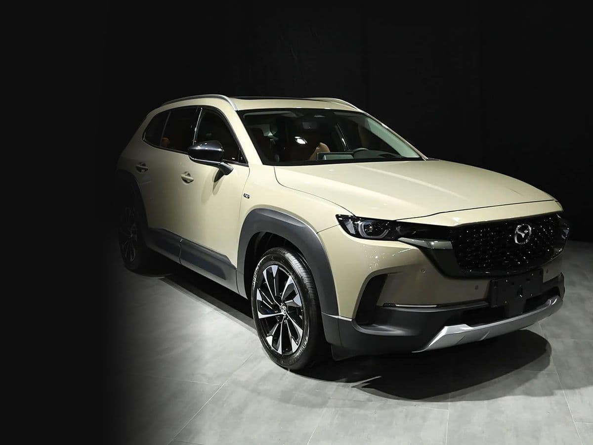 سيارة مازدا CX-50 Hybrid موديل 2023 الرياضية المدمجة في صالة عرض داكنة، منظر أمامي جانبي